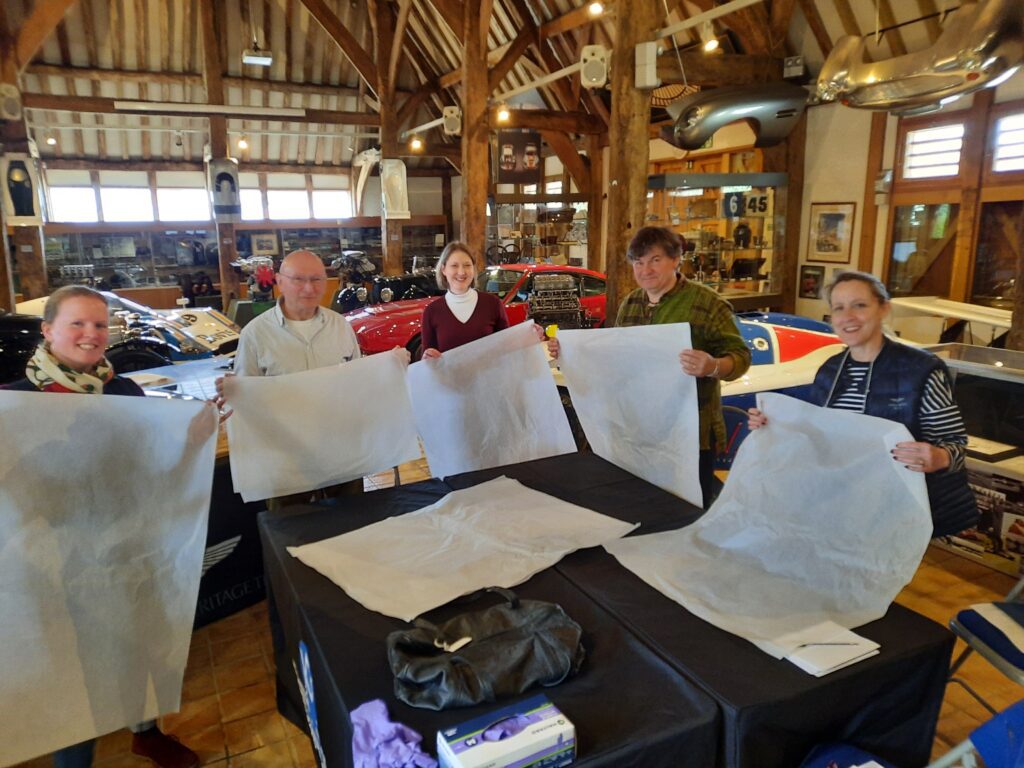 Photograph of the team holding sheets of tissue paper for making tissue puffs