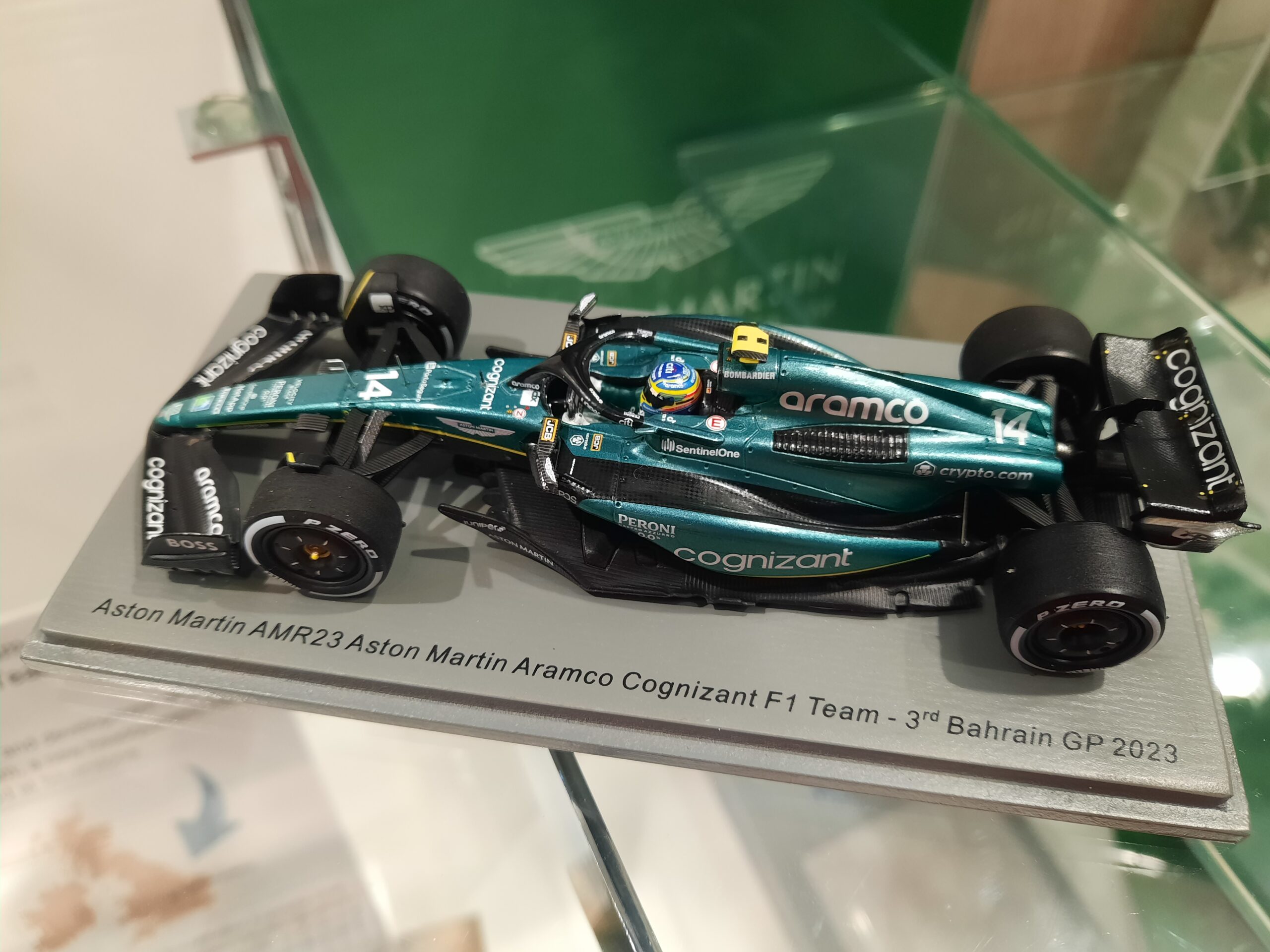 Image of a scale model of AMR23, the Aston Martin Aramco Cognizant F1 Team car, in metallic green livery. On the mount for the model is the inscription 'Aston Martin AMR23 Aston Martin Aramco Cognizant F1 Team - 3rd Bahrain GP 2023'