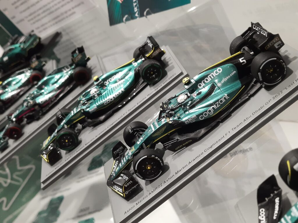 Diagonal image of Aston Martin F1 team car scale models displayed in a row, the front model is of AMR22 at the Abu Dhabi GP 2022