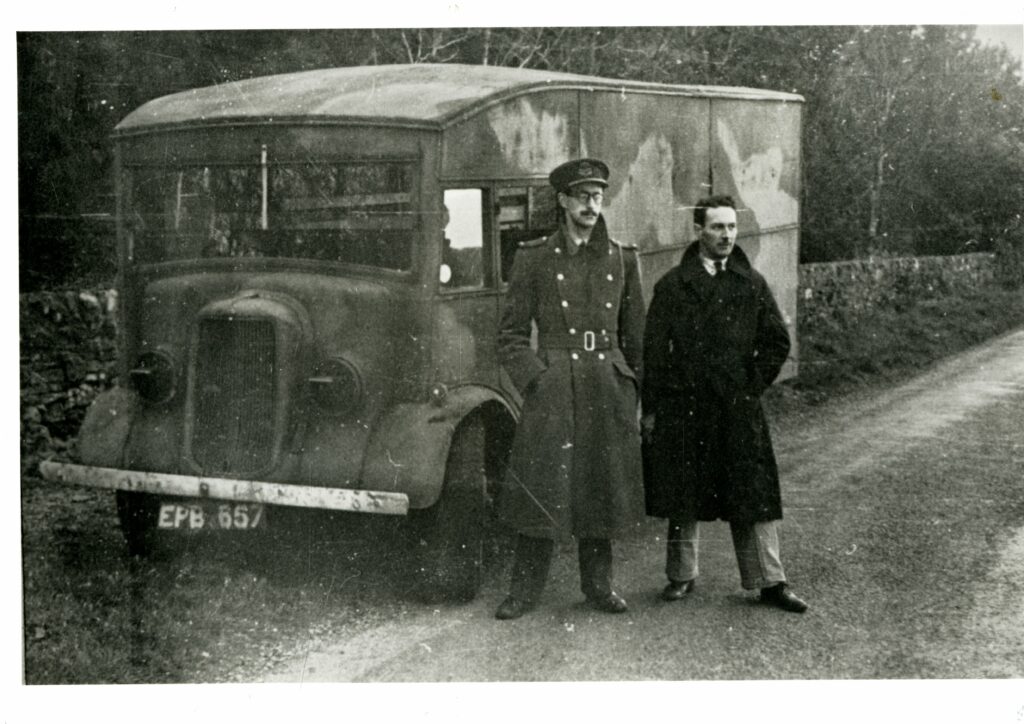 Black and white photograph of Charles Cholmondeley and Jock Horsfall stood in front of the van used to transport the body of 'Major Martin'. Taken 18th April 1943, Langbank, River Clyde