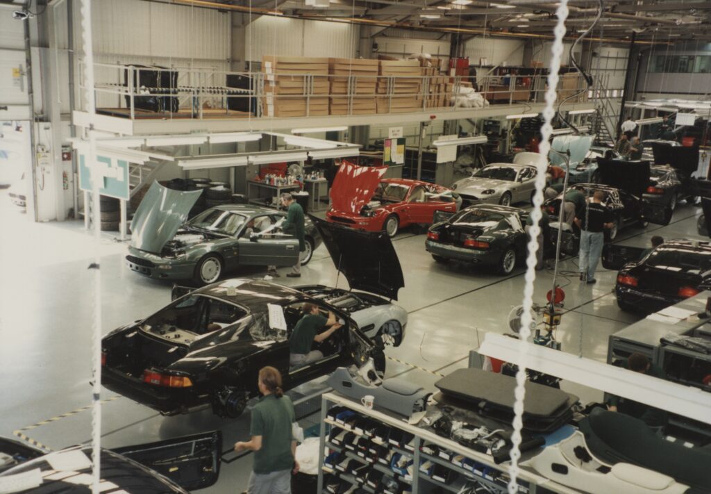 Colour photograph of the interior of AML's Bloxham factory, showing cars being worked on with their bonnets up