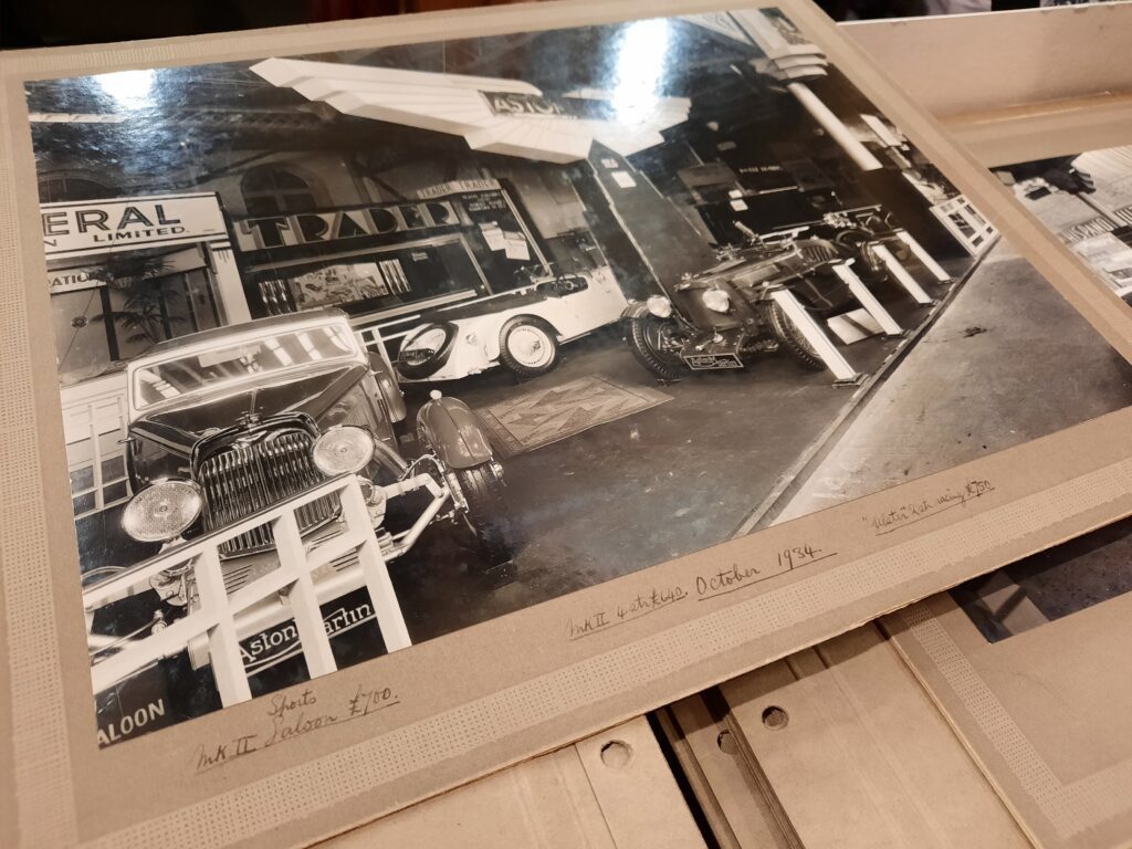 Close up of the handwritten notes around a black and white image of Aston Martins at the London Motor Show in October 1934