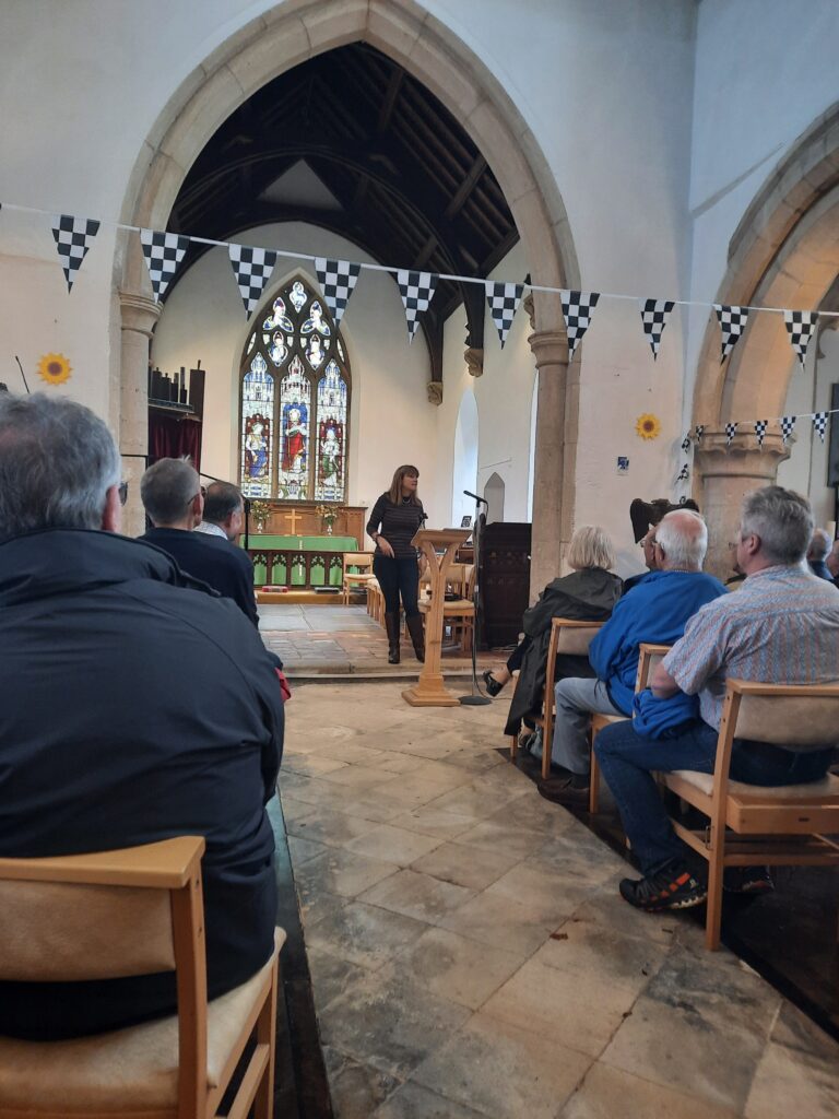Michelle McDermott speaks about Louis Zborowski inside St James Church. Racing bunting can be seen hanging from the columns