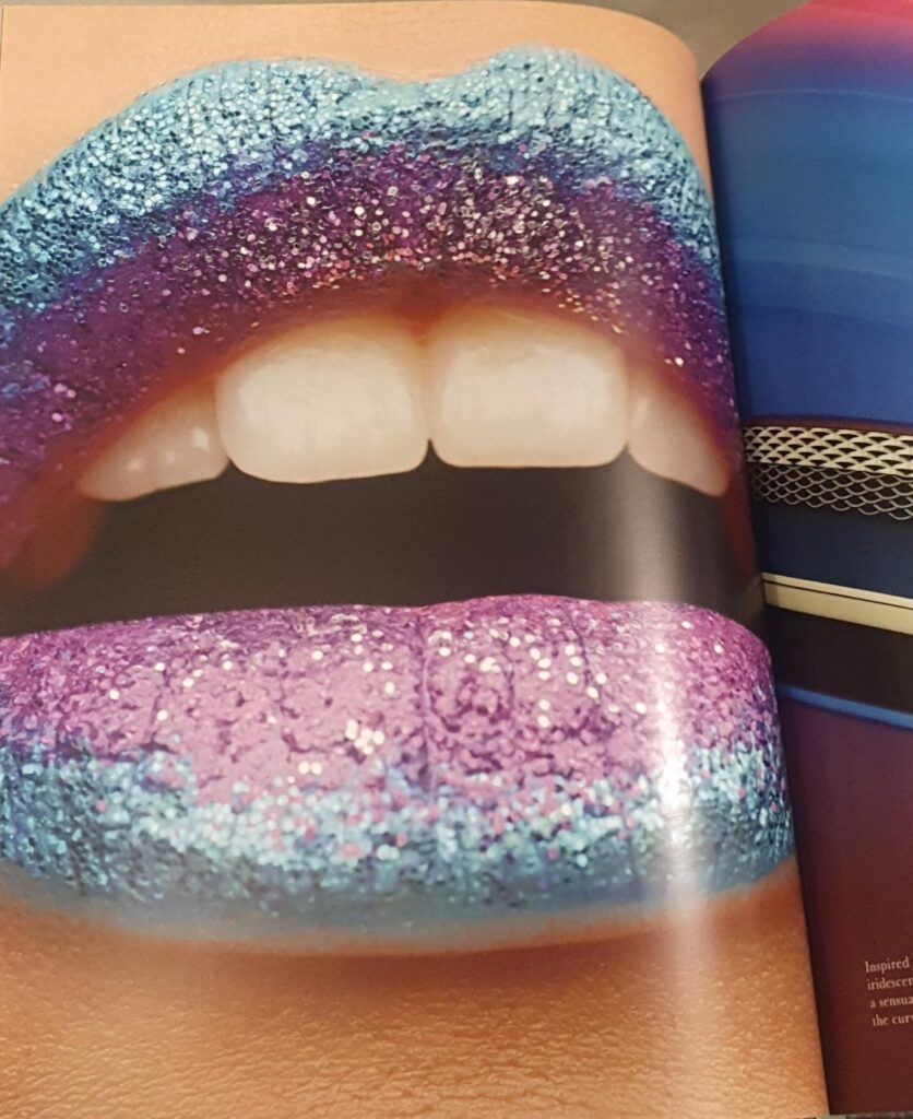 Image shows an interior page of the marketing brochure which depicts a large pair of glittery painted lips in blue and purple